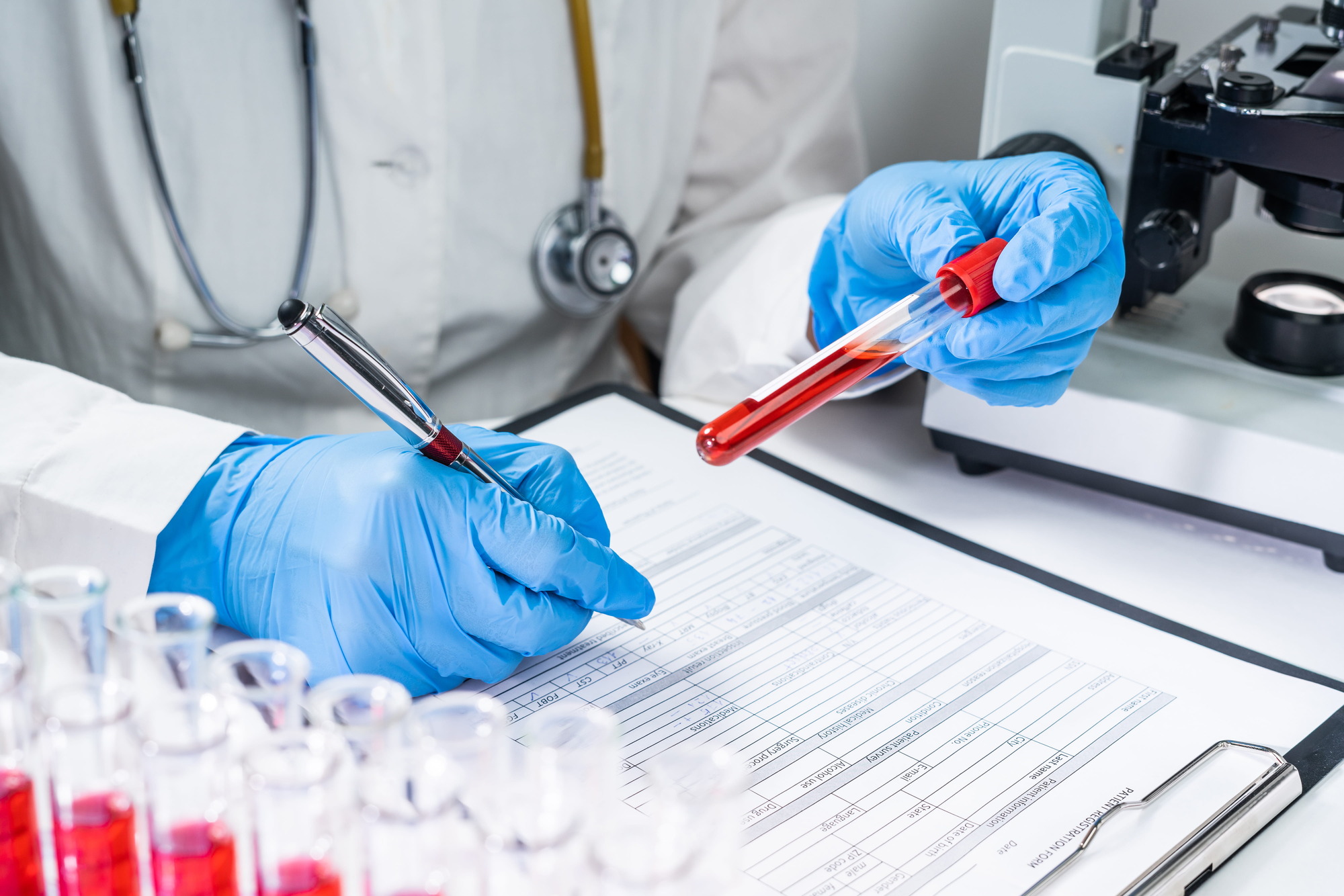 Medical technologist holding a sample while writing down the results of a test.