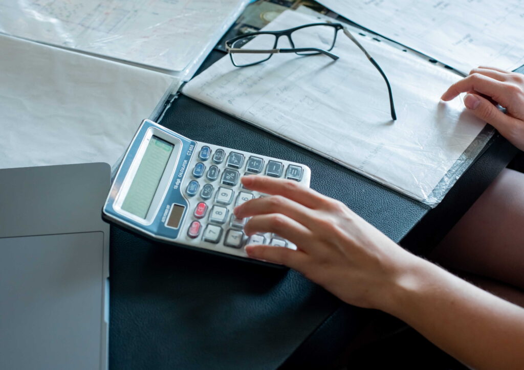 Close up view of hands using the calculator to calculate operational costs.